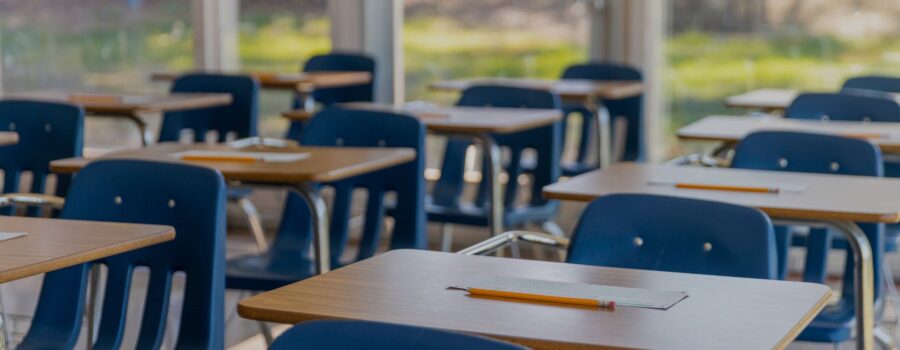 school desks with pencils and a piece of paper