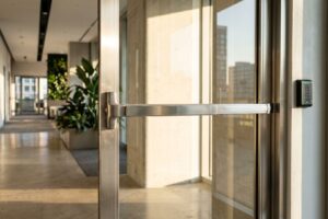 Modern commercial glass door featuring heavy-duty stainless steel push bars and a secure electronic card reader system.